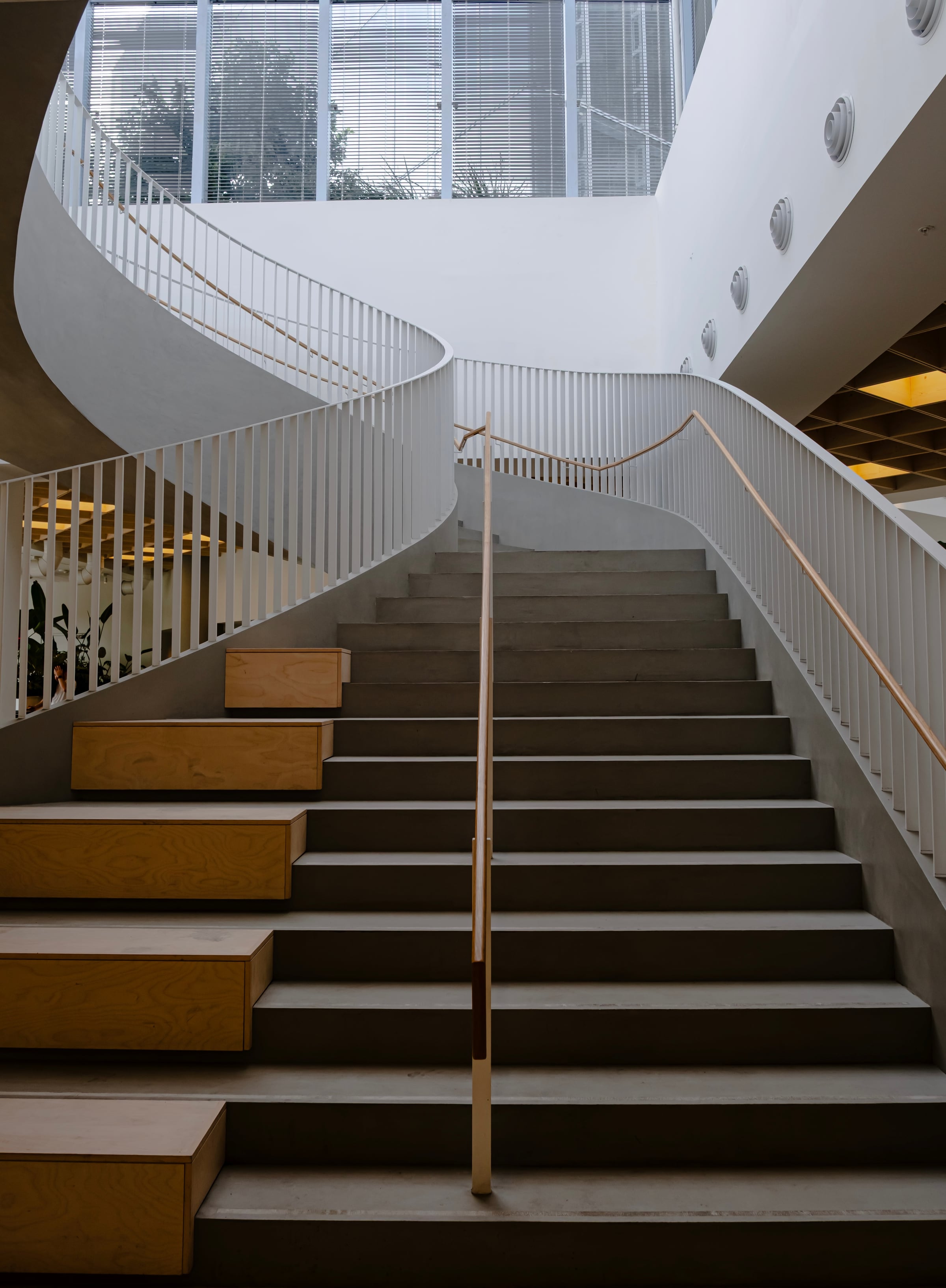 Modern building interior with curved white spiral staircase and wood steps